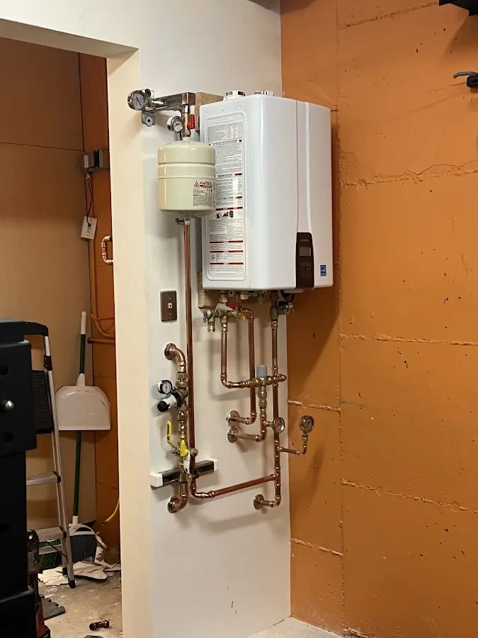 Plumbing technician inspecting water heater connections in McSwain